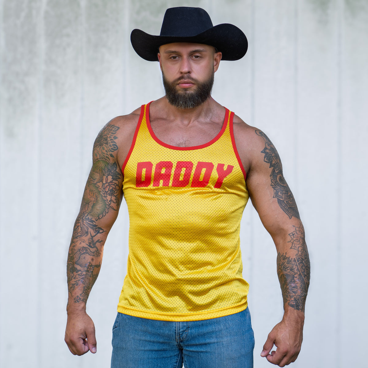 a gay tank top from gruff pup in yellow with daddy written on the front made of stretchy mesh for gay men