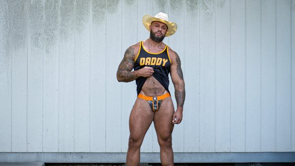 Model Stuart wearing a black Daddy Air Tank with an orange Gruff Pup Combat Jockstrap